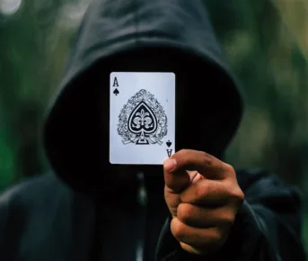 Hætteklædt mand hackede spilleautomater skjuler sit ansigt med spillekort
